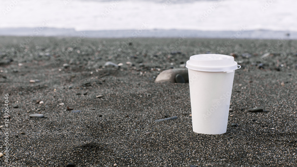 two disposable white and black coffee cardboard cup against the backdrop of the sea coast, sandy seashore, pebble beach. mock up, place for logo two disposable white and black coffee cardboard cup against the backdrop of the sea coast, sandy seashore, pebble beach. mock up, place for logo