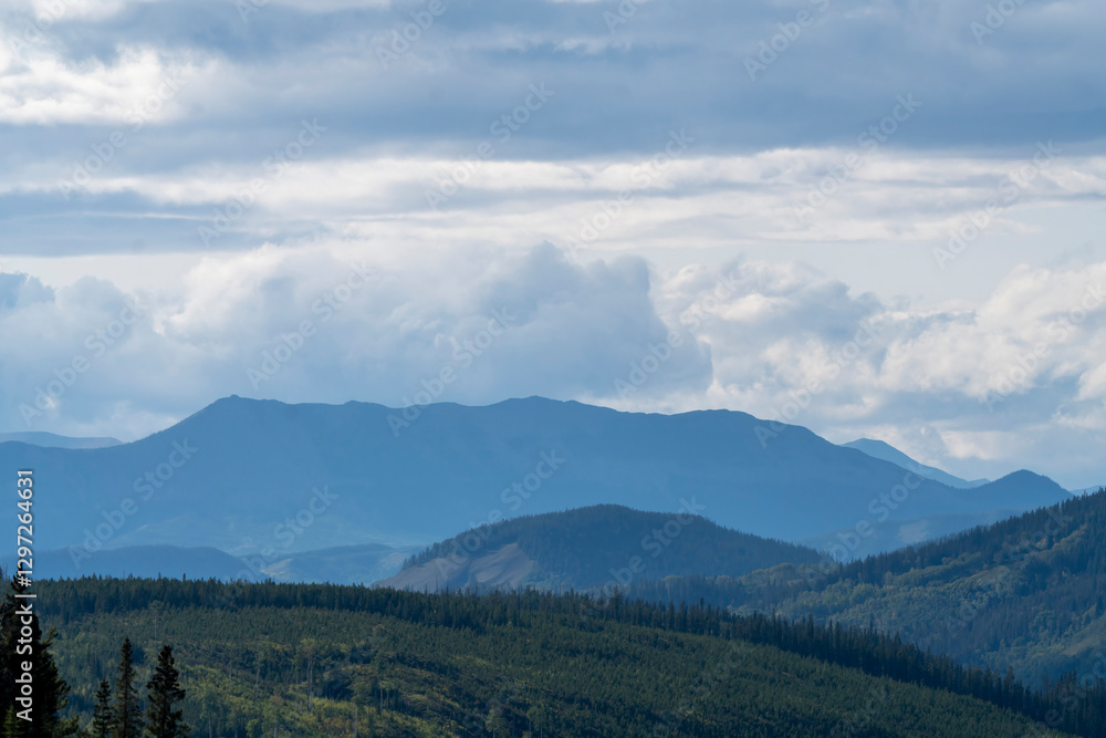 Fototapeta premium Breathtaking mountain range covered by forest under cloudy sky