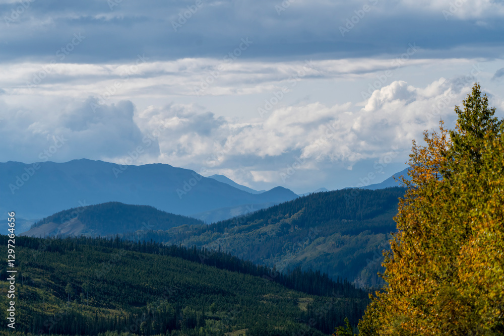 Fototapeta premium Rolling hills and distant peaks under cloudy sky in british columbia