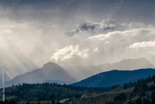 Sun rays shining through clouds over rocky mountains