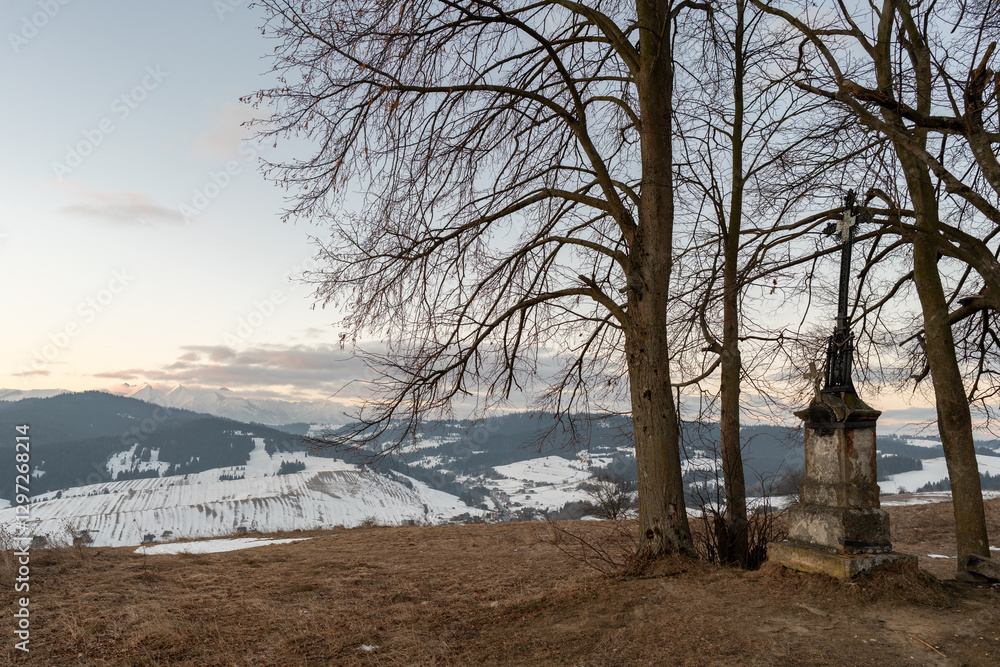 Stara kapliczka z krzyżem w Pieninach. Widok na ośnieżone Tatry