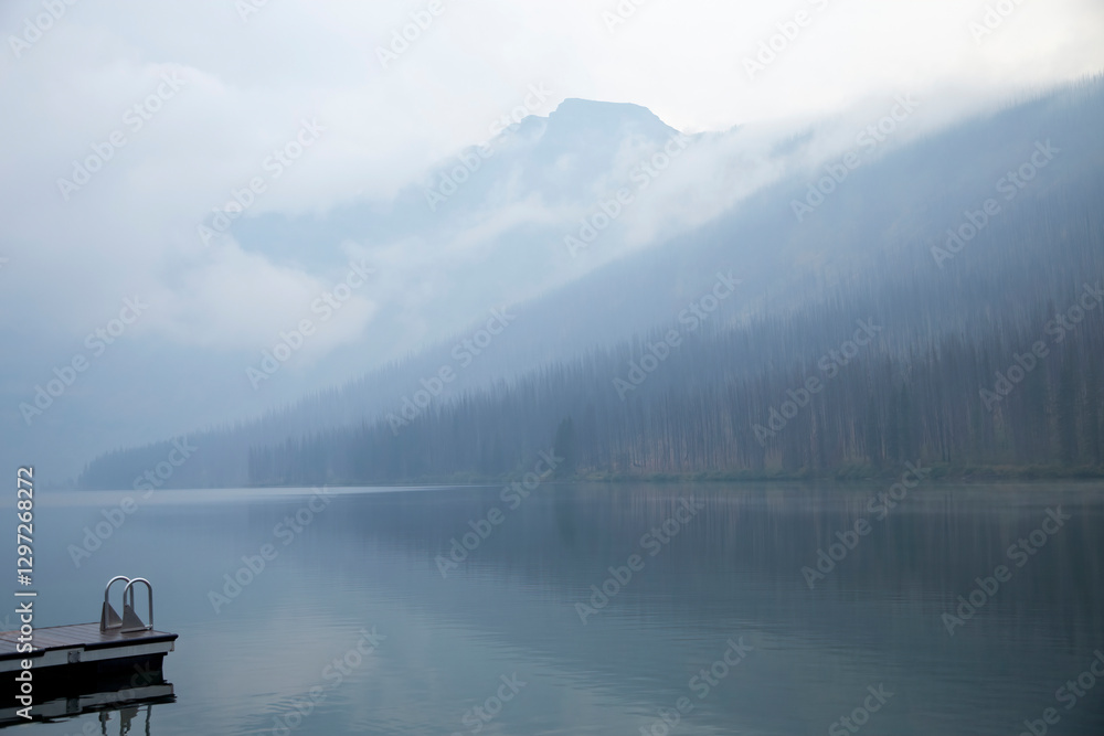 Fog hanging over mountain lake and forest with dock