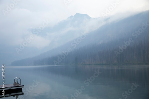 Obraz na płótnie Fog hanging over mountain lake and forest with dock w salonie