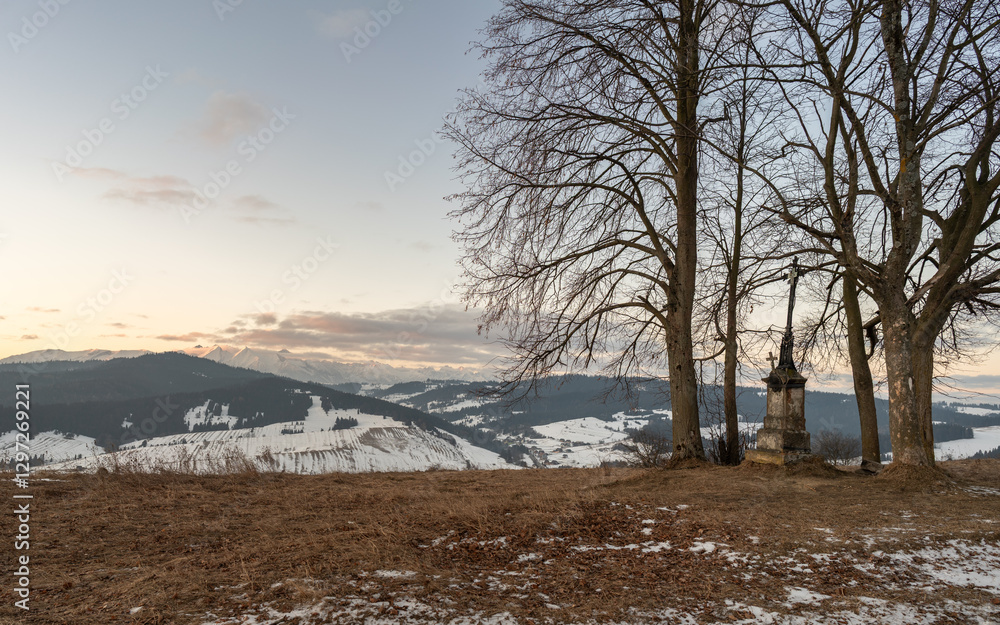 Stara kapliczka z krzyżem w Pieninach. Widok na ośnieżone Tatry