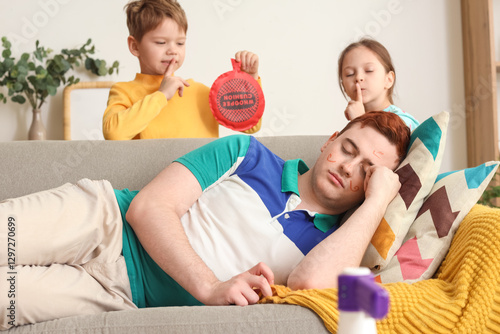 Tableau sur toile Little children planning to prank their sleeping father with whoopee cushion at home