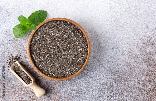 Chia seeds in a wooden bowl on a gray background, close-up. Top view