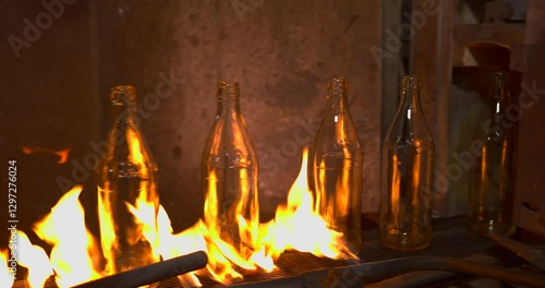 glass bottles pass through flames on a conveyor belt during fire annealing in an industrial factory improving durability and strength in the manufacturing process of high-quality glass containers