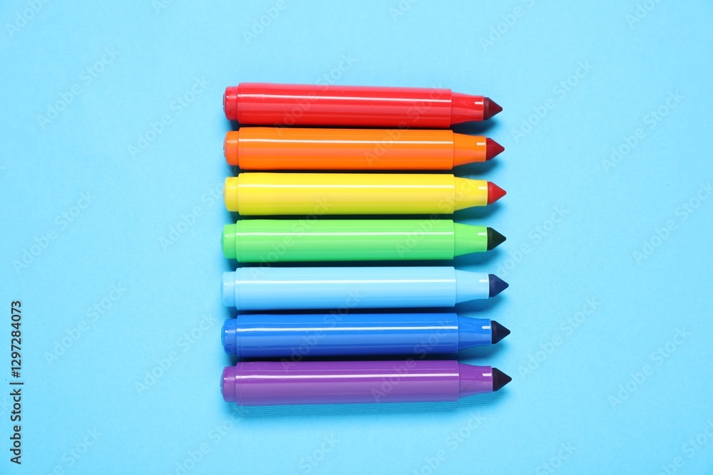 Fototapeta premium Many colorful markers on light blue background, flat lay