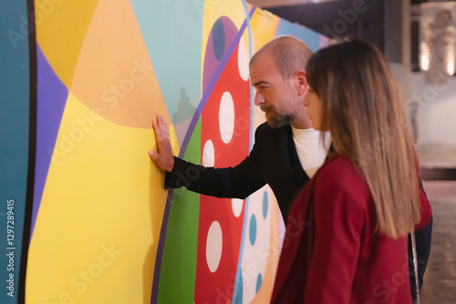 Tableau sur toile Art curator showing colorful modern painting to potential buyer