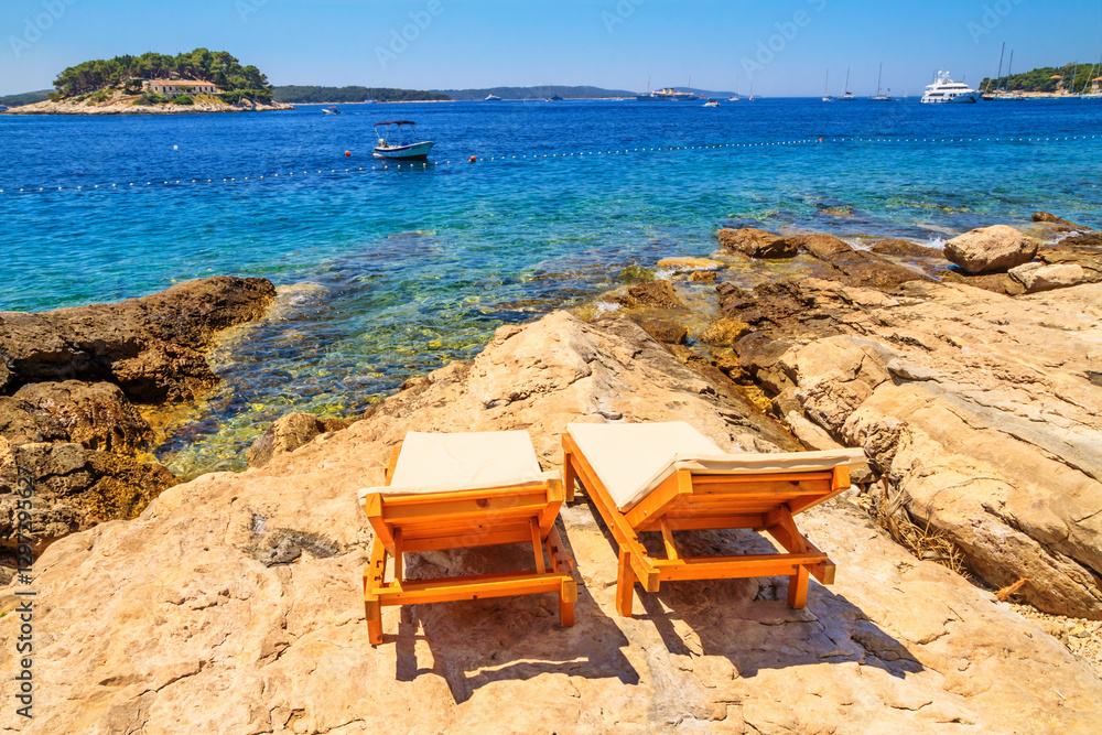 Coastal summer landscape - view of the beach loungers on a rocky seashore, on the island of Hvar, the Adriatic coast of Croatia