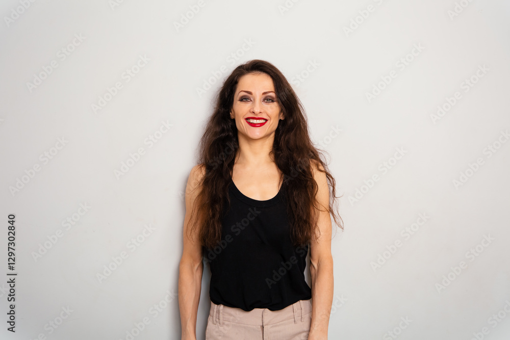 Positive relaxing make-up woman with red lipstick, long brown hair looking happy in black summer top on blue studio empty copy space background. Expression front view portrait Positive relaxing make-up woman with red lipstick, long brown hair looking happy in black summer top on blue studio empty copy space background. Expression front view portrait