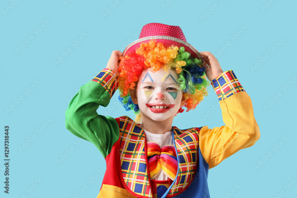 Funny little boy in clown disguise with hat on blue background. April Fool's Day celebration Funny little boy in clown disguise with hat on blue background. April Fool's Day celebration
