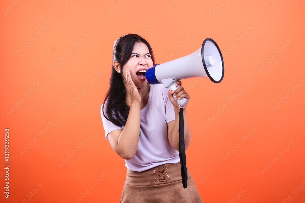 A person holding and speaking into a megaphone on an orange background A person holding and speaking into a megaphone on an orange background