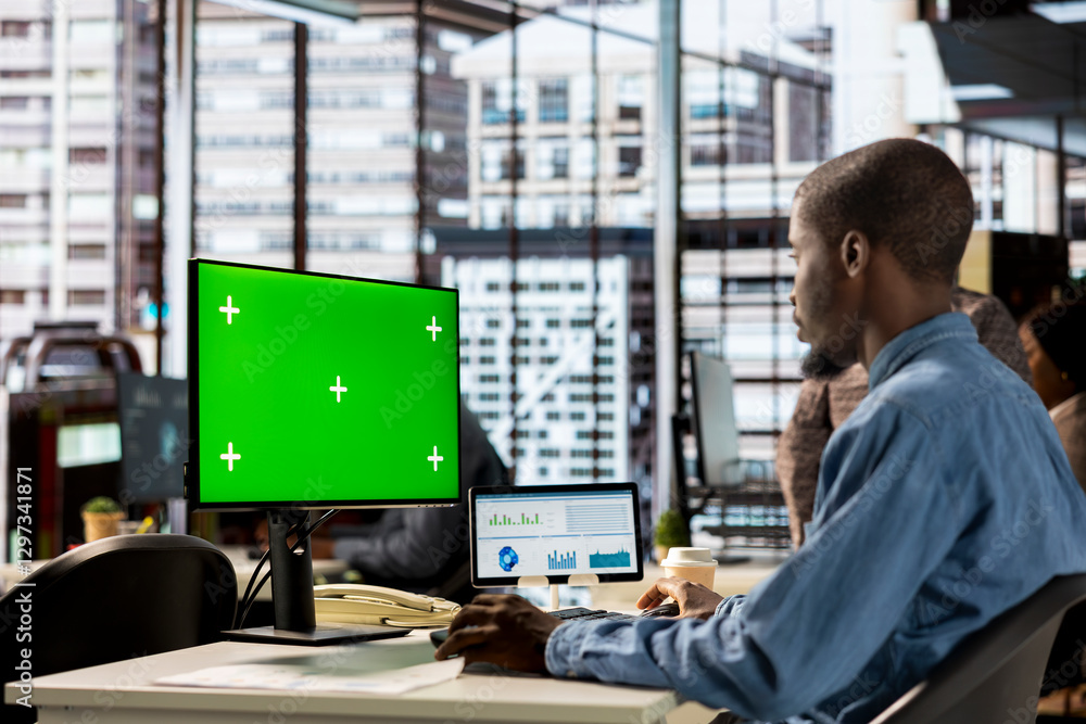 Black businessman analyzing financial data next to chroma key screen, reviewing company strategies on computer and contributing to business development and decision making. Successful forecast. Black businessman analyzing financial data next to chroma key screen, reviewing company strategies on computer and contributing to business development and decision making. Successful forecast.