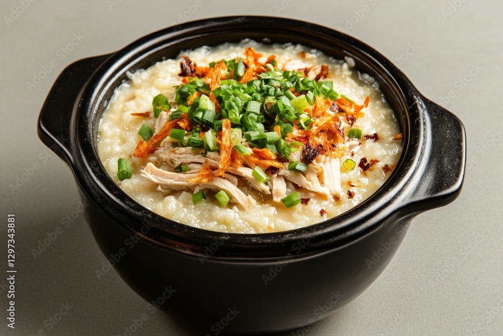Savory chicken congee with scallions and crispy onions in black ceramic bowl Savory chicken congee with scallions and crispy onions in black ceramic bowl