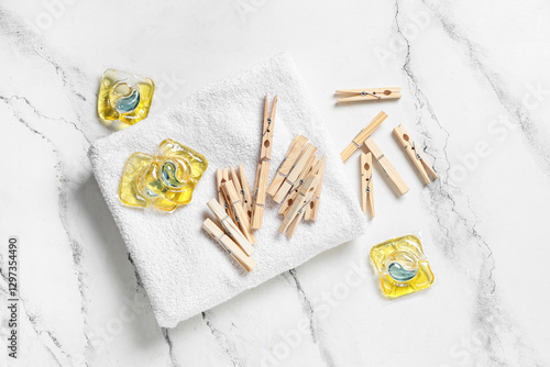 Wooden clothespins with clean towel and gel capsules on grunge white background