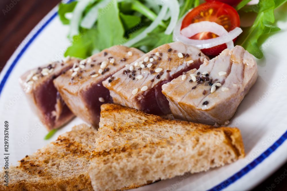 Deliciously lightly fried tuna with toasted bread, served with greens and tomatoe Deliciously lightly fried tuna with toasted bread, served with greens and tomatoe