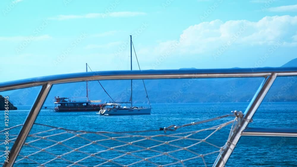 Calm yacht sailing during vacation time. A view of big ships with no sails have a sea cruise on waves against clear sunny horizon in summer.