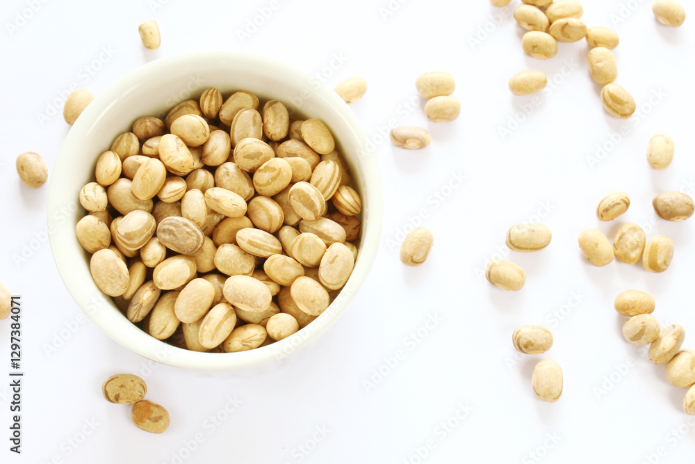 Carioca beans in a bowl and grains scattered on the white background. Carioca beans in a bowl and grains scattered on the white background.