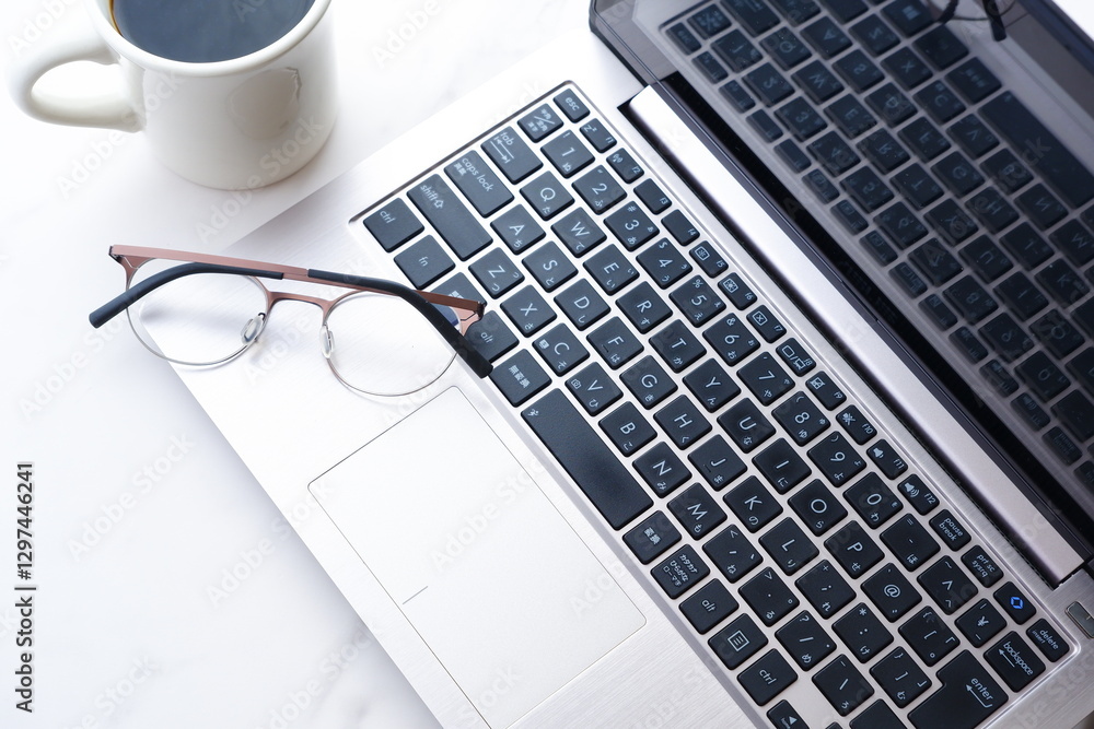 コーヒーを飲みながらノートパソコンでデスクワークをしているイメージ
