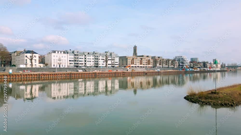 Scenic view of Arnhem's urban riverfront with modern residential buildings reflecting in calm water. The Rhine River and city architecture are prominent. Arnhem, Gelderland, Netherlands.