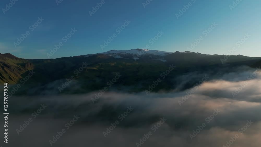 Snow-capped Peak Of Eyjafjallajokull Mountain In South Iceland With Cloud Inversion In Foreground. side drone shot Snow-capped Peak Of Eyjafjallajokull Mountain In South Iceland With Cloud Inversion In Foreground. side drone shot