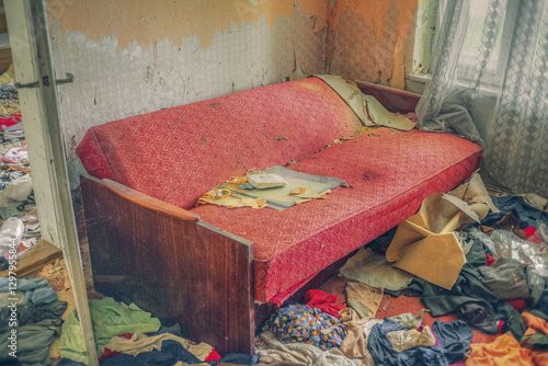 фотографія Destroyed sofa inside abandoned apartment surrounded by trash and discarded clot
