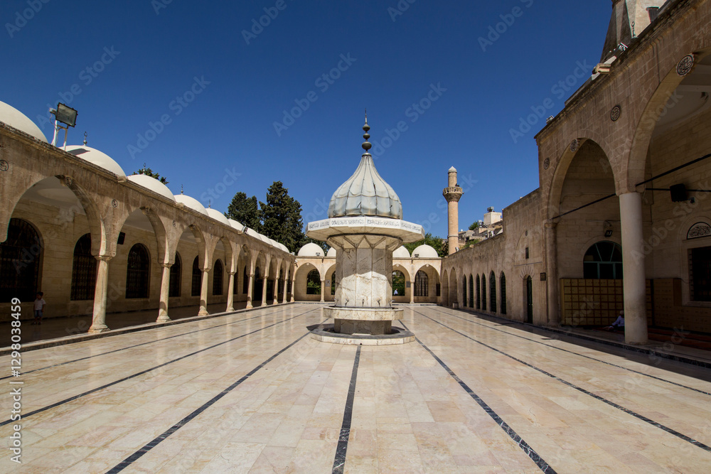 Fototapeta premium Sanliurfa Urfa Turkiye Turkey Tranquil Courtyard of a Historic Mosque in Middle East. A serene courtyard within historical mosque showcasing intricate architectural details and a beautiful fountain