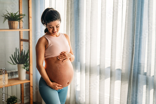 Free Download Fit pregnant woman holding hands on her belly, enjoying in the last trimester of pregnancy. - GFXLoad