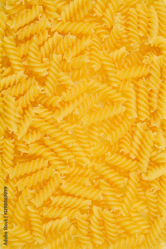 A close-up, top-down shot of uncooked fusilli pasta, showcasing its spiral shape and golden color A close-up, top-down shot of uncooked fusilli pasta, showcasing its spiral shape and golden color
