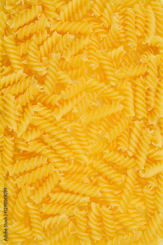 A close-up, top-down shot of uncooked fusilli pasta, showcasing its spiral shape and golden color