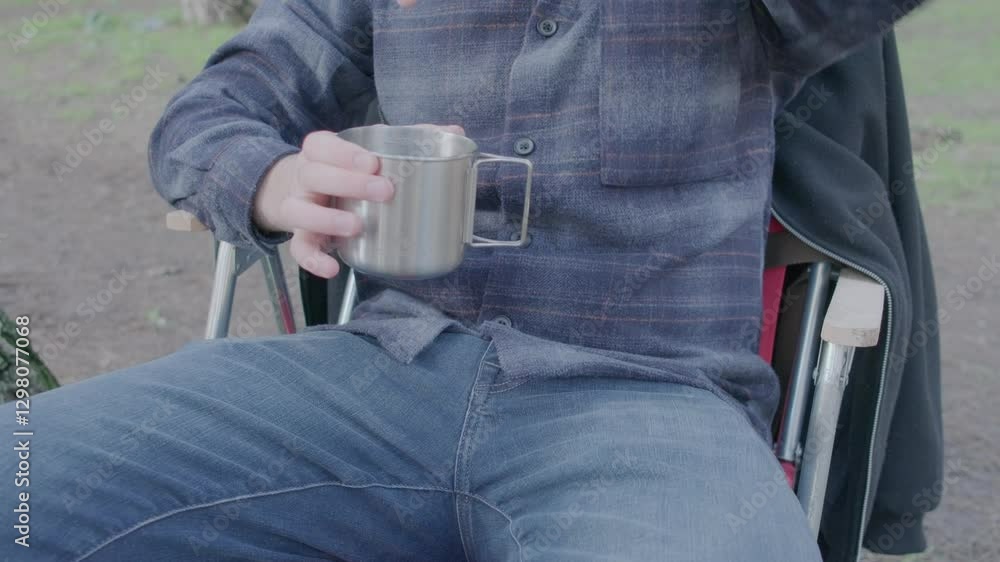 oung man with lumberjack shirt sitting on chair in forest camp and drinking coffee from metal cup
oung man with lumberjack shirt sitting on chair in forest camp and drinking coffee from metal cup