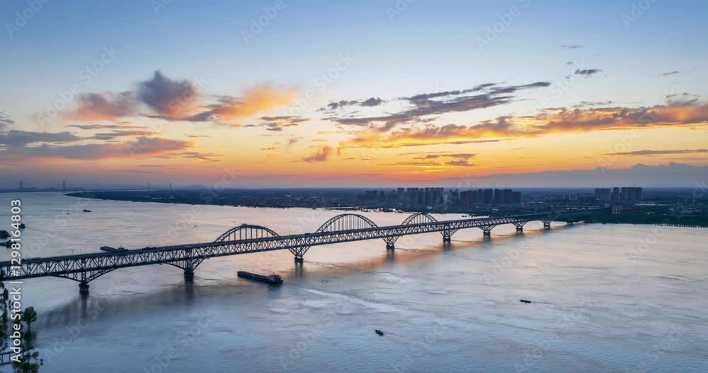 aerial time lapse video of Jiujiang Yangtze river bridge under the summer sky with fiery clouds. the chinese characters on the bridge tower read: aerial time lapse video of Jiujiang Yangtze river bridge under the summer sky with fiery clouds. the chinese characters on the bridge tower read: