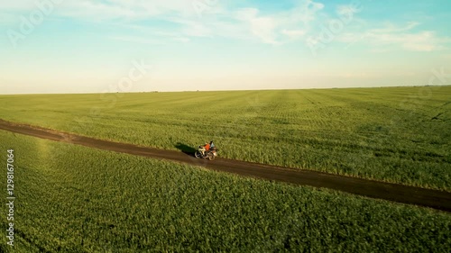 A motorcycle rides among green fields