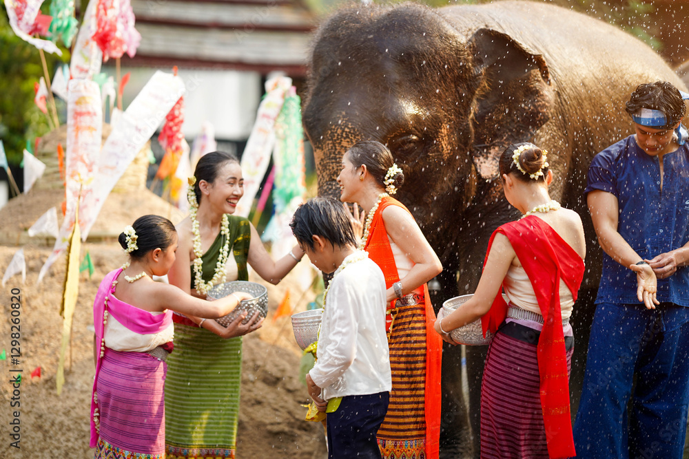 Group of Thai teenager in the Thai traditional dress play to sprinkle water on the Thai New Year's Day or Songkran festival in a fun way with elephant outdoors Group of Thai teenager in the Thai traditional dress play to sprinkle water on the Thai New Year's Day or Songkran festival in a fun way with elephant outdoors