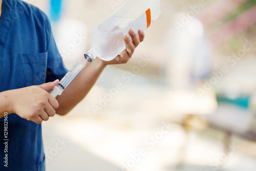 Closeup veterinarian is using saline in a syringe to wash out the inflamed eyes of a sick elephant in the elephant hospital.