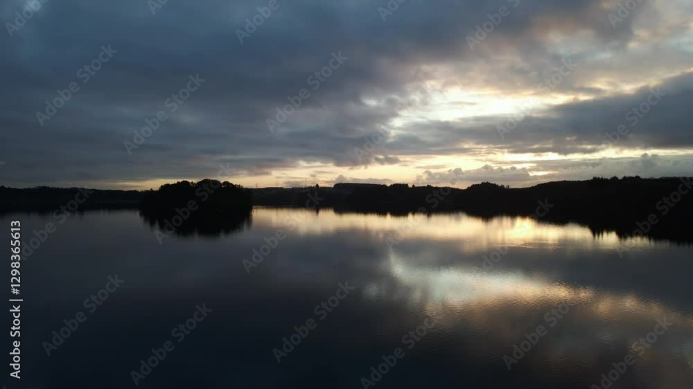 Aerial Drone Shot Over Calm Water at Cloudy Dusk with Silhouettes Aerial Drone Shot Over Calm Water at Cloudy Dusk with Silhouettes