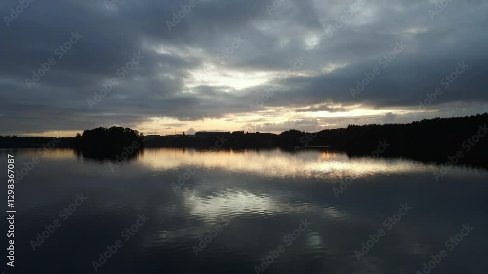 Aerial Drone Shot Over Calm Water at Cloudy Dusk with Silhouettes Aerial Drone Shot Over Calm Water at Cloudy Dusk with Silhouettes