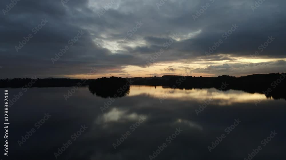 Aerial Drone Shot Over Calm Water at Cloudy Dusk with Silhouettes Aerial Drone Shot Over Calm Water at Cloudy Dusk with Silhouettes