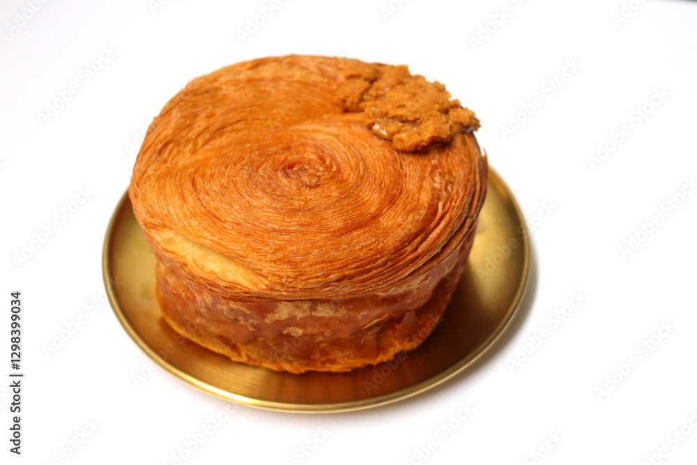Croissant roll or timbering on yellow metal round dish on white background. Croissant roll or timbering on yellow metal round dish on white background.
