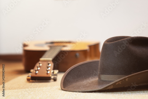 brown cowboy hat and acoustic guitar out of focus in background - country music and line dance - text space on top