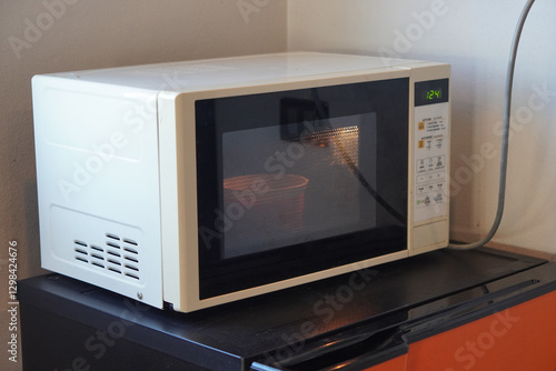 side view white microwave oven placed on an orange and black refrigerator, white wall background, object, hot, technology, copy space