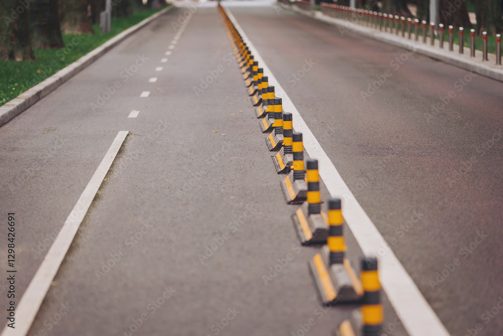 A long stretch of road features bright yellow and black safety barriers, ensuring smooth traffic flow in a peaceful urban environment during the afternoon light A long stretch of road features bright yellow and black safety barriers, ensuring smooth traffic flow in a peaceful urban environment during the afternoon light