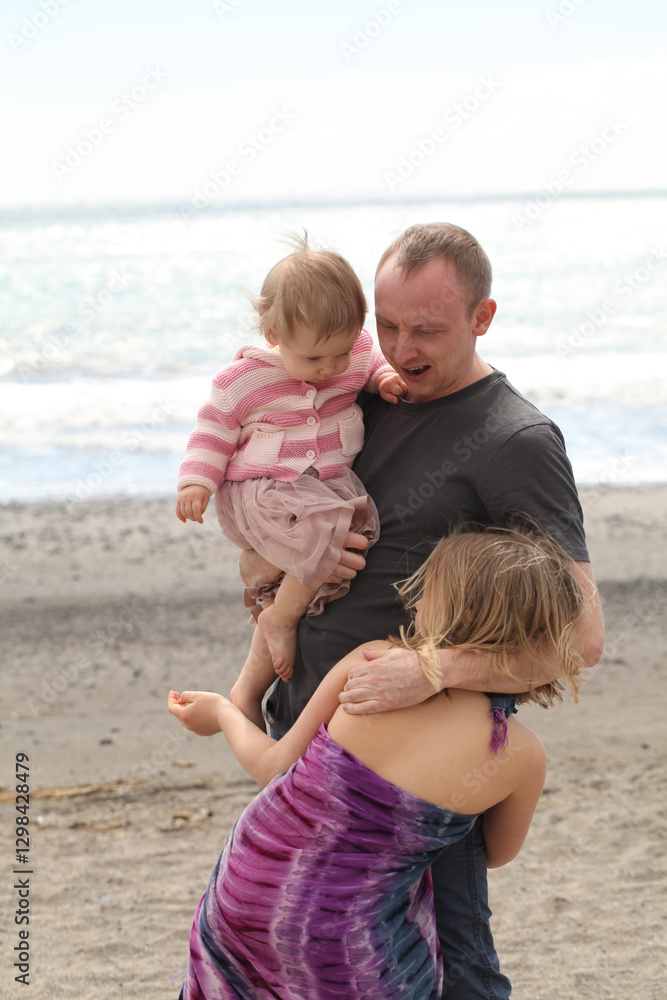 Happy family. Father and his two daughter playing at the sea beach. Young man and girl child outdoors Happy family. Father and his two daughter playing at the sea beach. Young man and girl child outdoors