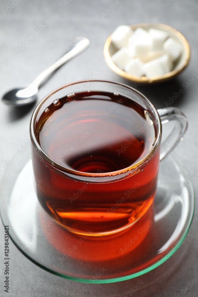 Refreshing black tea in cup on grey table, closeup Refreshing black tea in cup on grey table, closeup