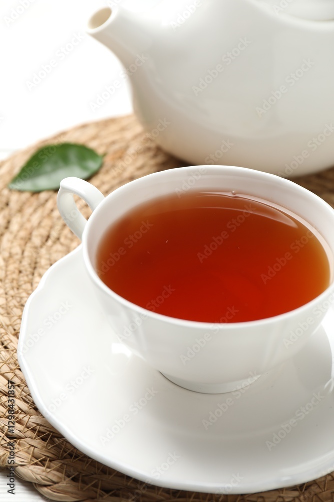 Aromatic black tea in cup and teapot on white table, closeup Aromatic black tea in cup and teapot on white table, closeup