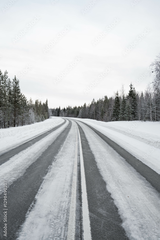 Obraz premium Snow covered road in North Finland on a sunny winter day. Travel Finland landscape background.