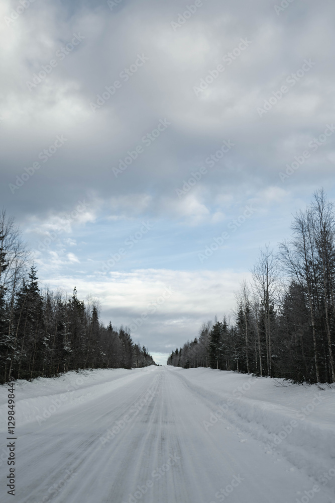 Obraz premium Snow covered road in North Finland on a sunny winter day. Travel Finland landscape background.