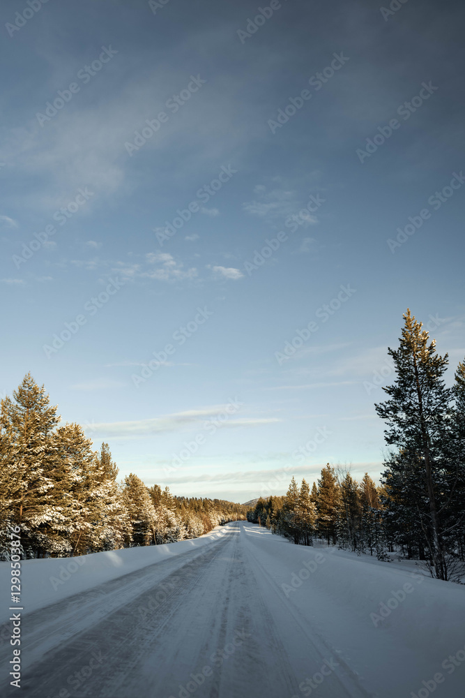 Obraz premium Snow covered road in North Finland on a sunny winter day. Travel Finland landscape background.