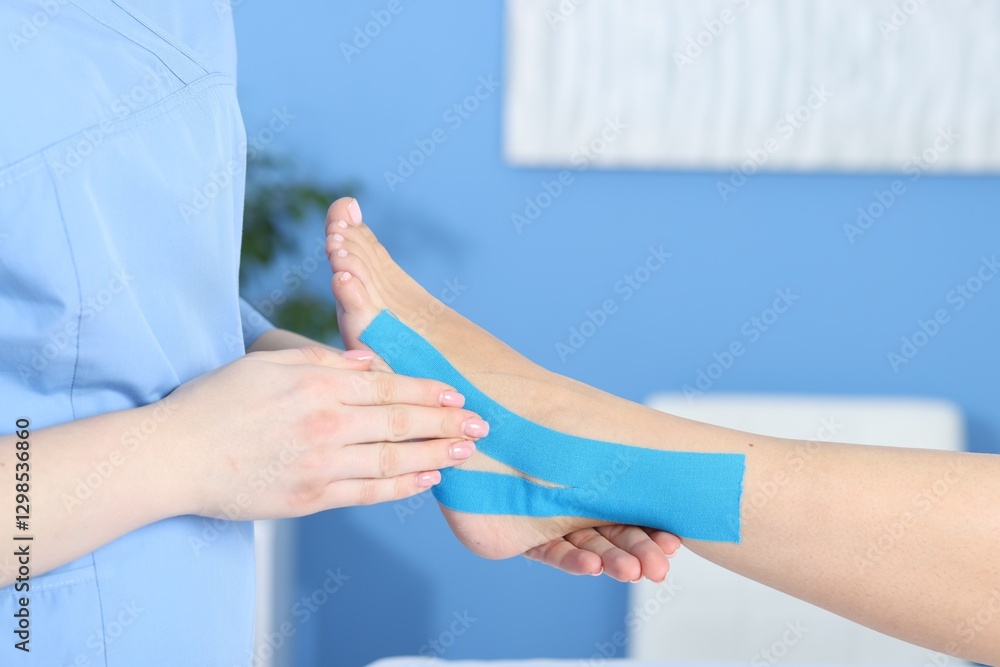 Obraz premium Doctor applying kinesio tapes to patient's foot in hospital, closeup